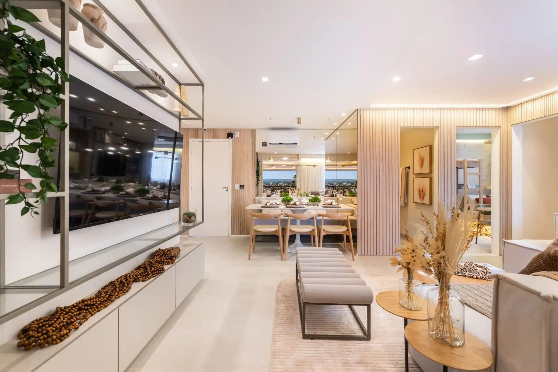 Sala de jantar integrada com mesa, cadeiras e painel ripado, conectada à área de estar.