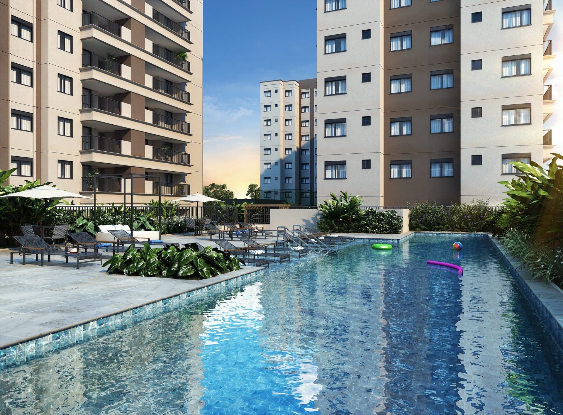 Piscina externa com deck, espreguiçadeiras, guarda-sóis e paisagismo ao redor dos prédios.