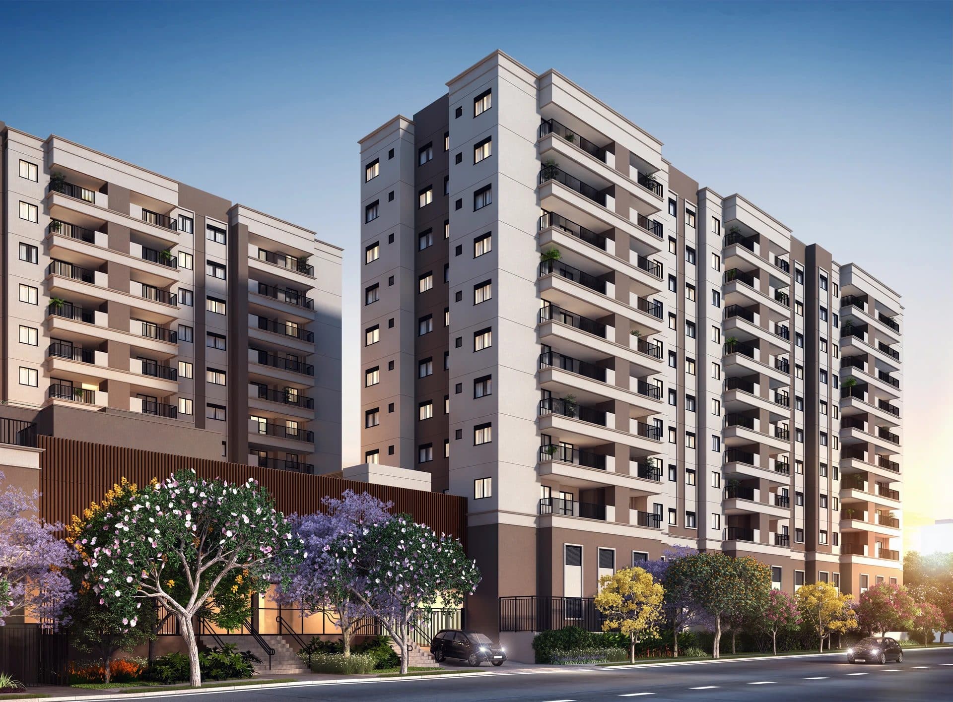 Fachada de condomínio residencial com paisagismo e árvores floridas na entrada.